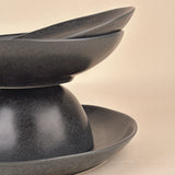 Set of three dark gray ceramic bowls stacked on a beige background