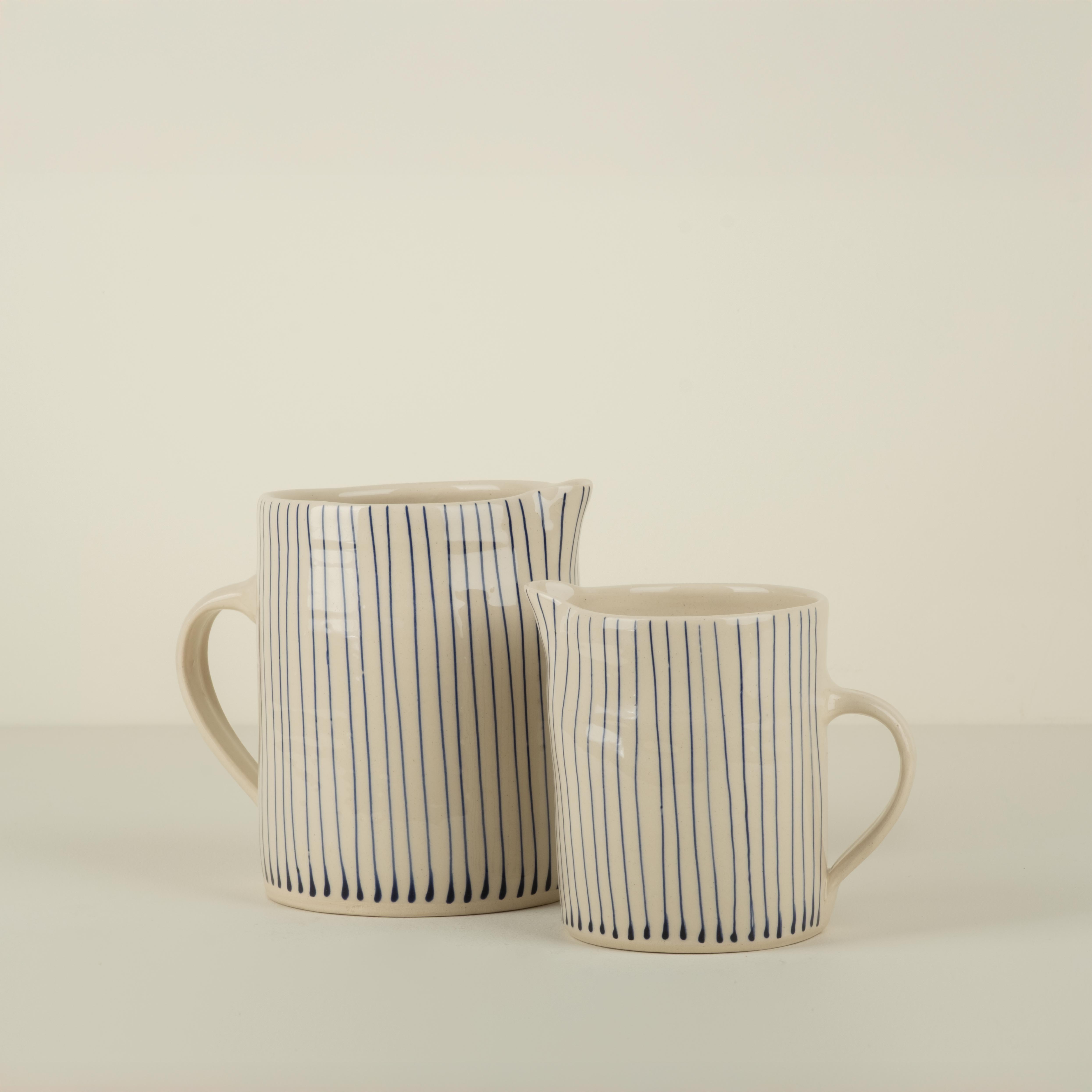 Two ceramic mugs with black striped patterns on a beige background