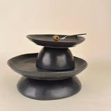 Black ceramic three-tiered stand on a beige background