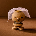 Wooden toy figure with a white headscarf on a brown background
