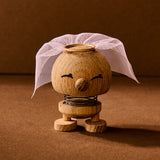 Wooden toy figure with a white headscarf on a brown background