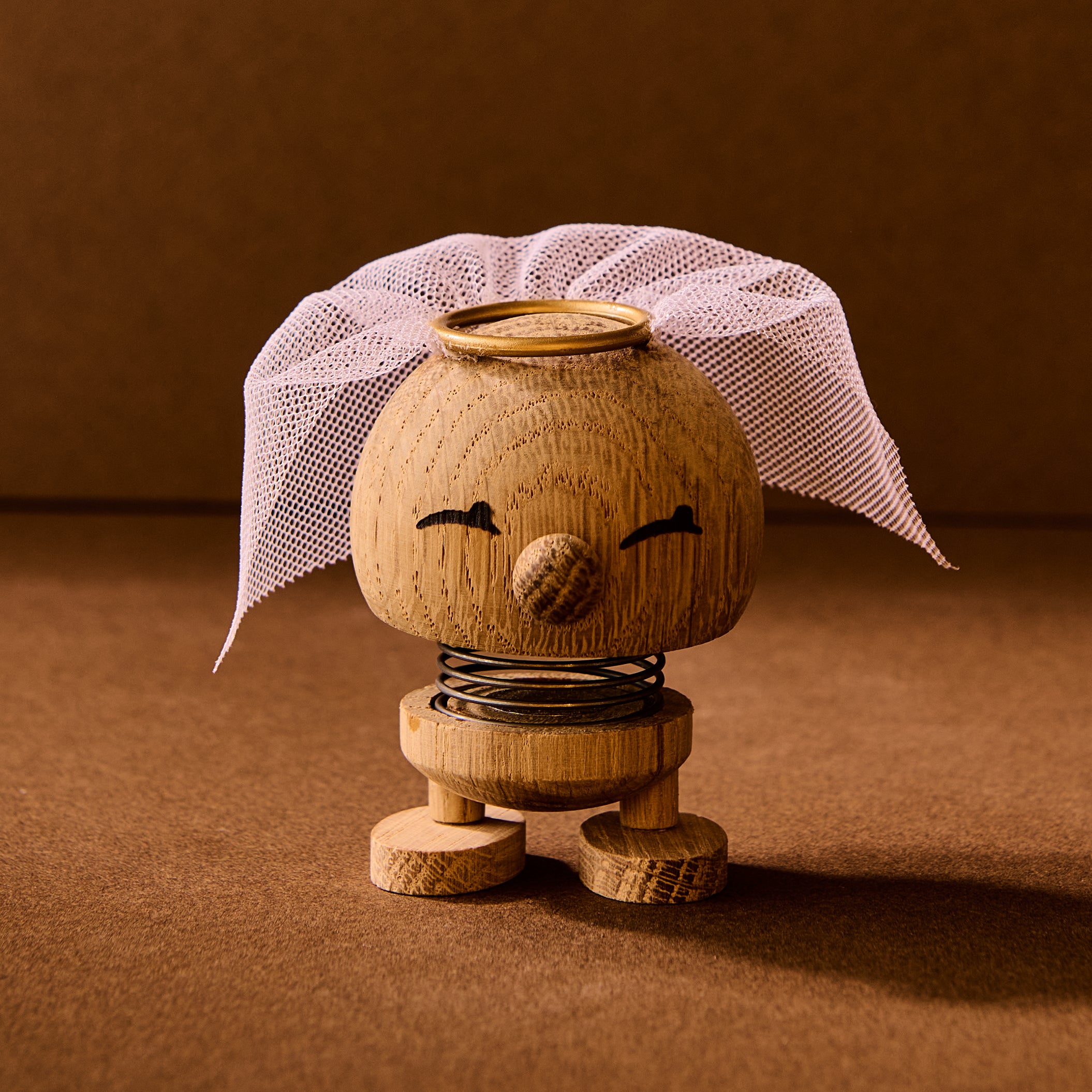 Wooden toy figure with a white headscarf on a brown background