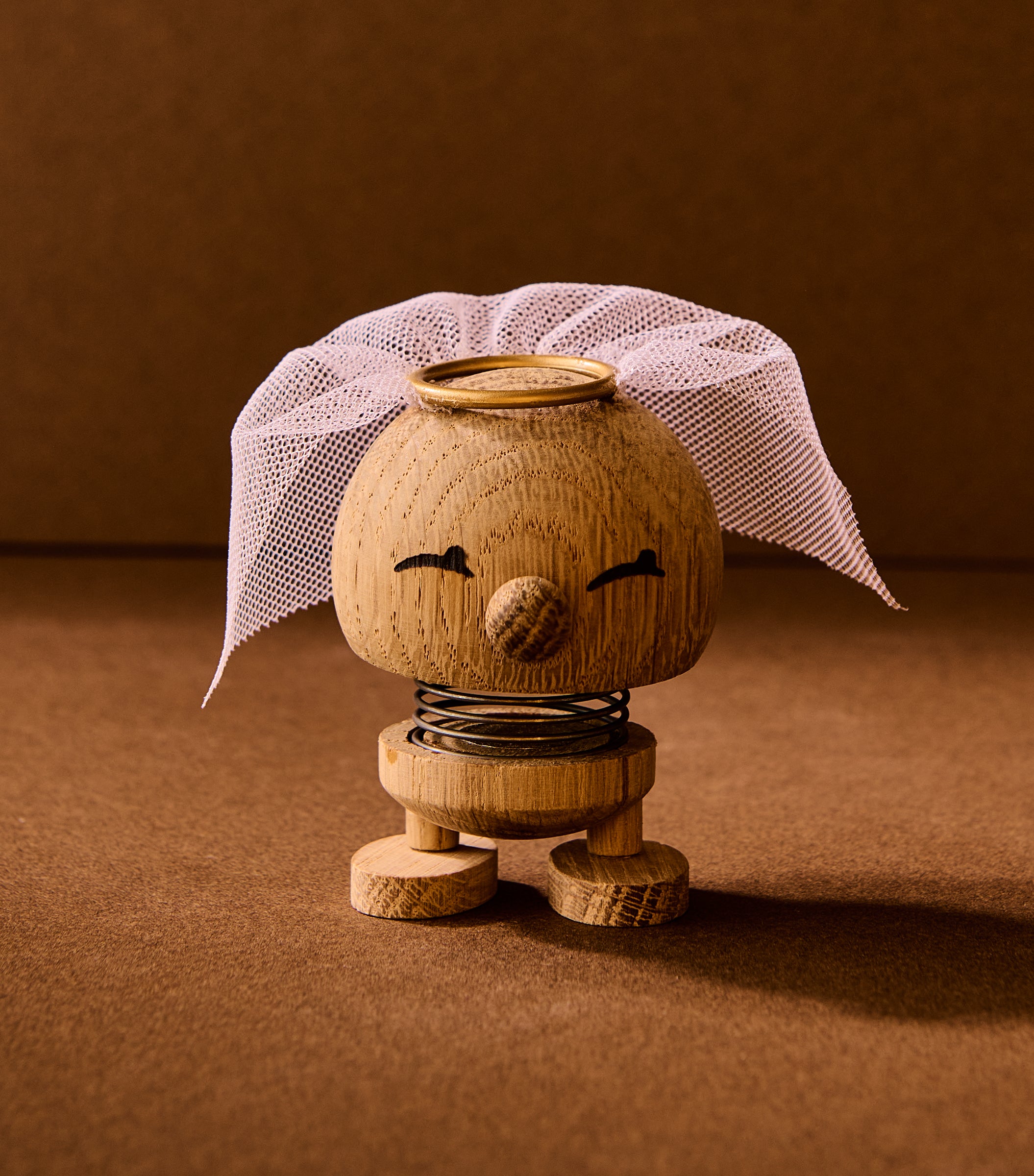 Wooden toy figure with a white headscarf on a brown background