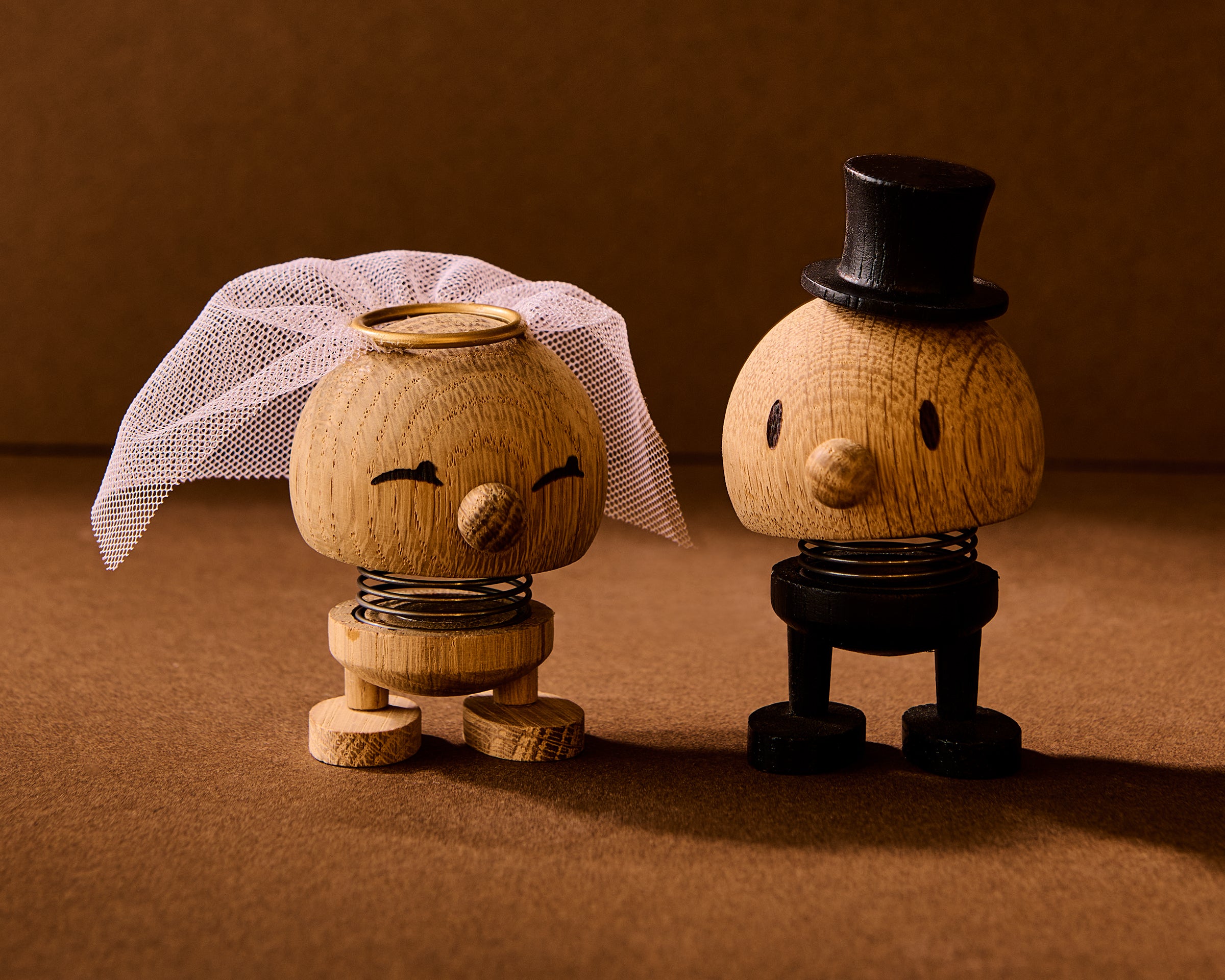 Wooden figurines of a bride and groom on a brown background