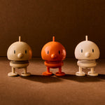 Three small robot figurines in beige, orange, and white on a brown background