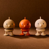 Three small robot figurines in beige, orange, and white on a brown background