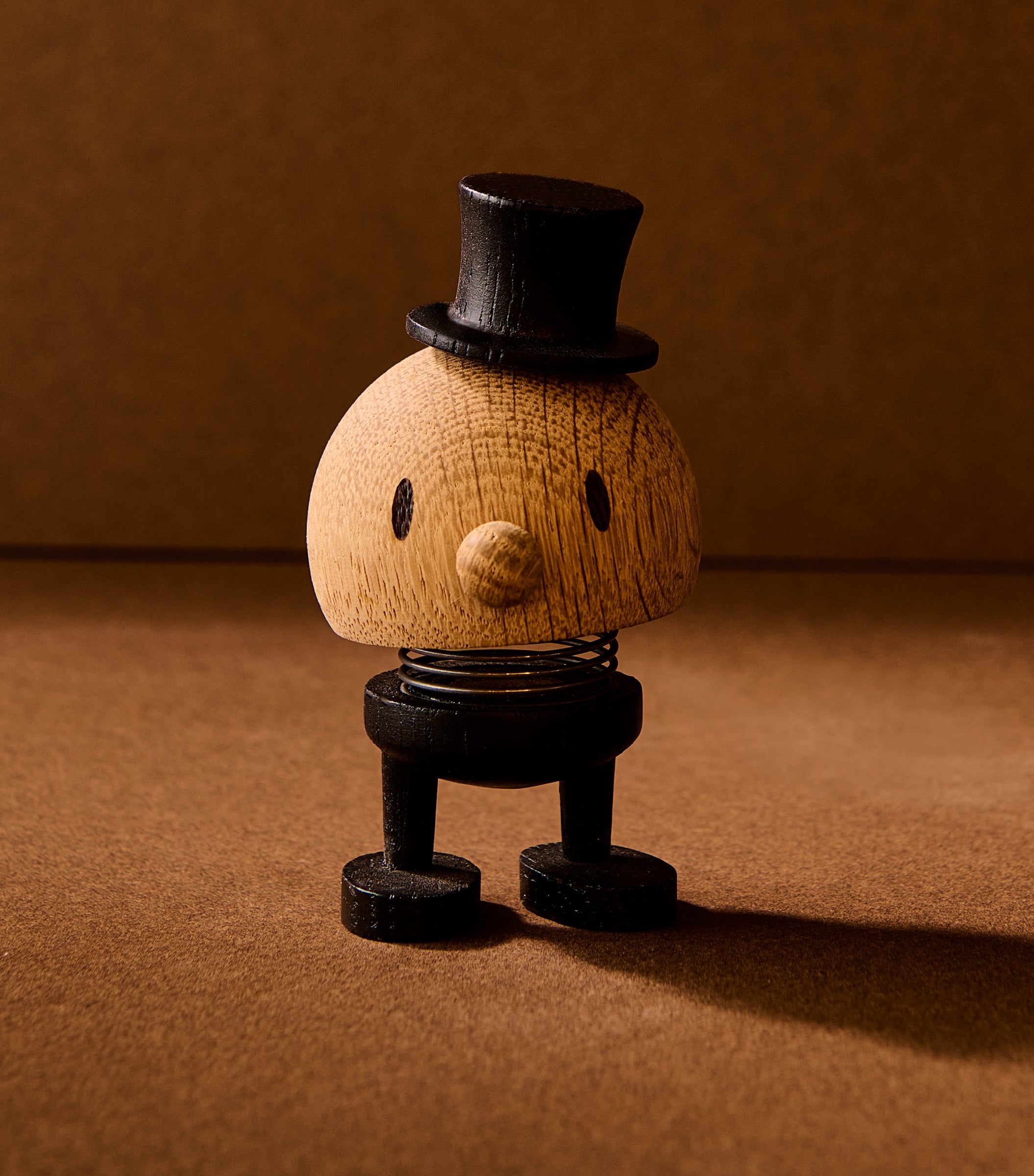 Wooden figurine with a top hat on a brown background