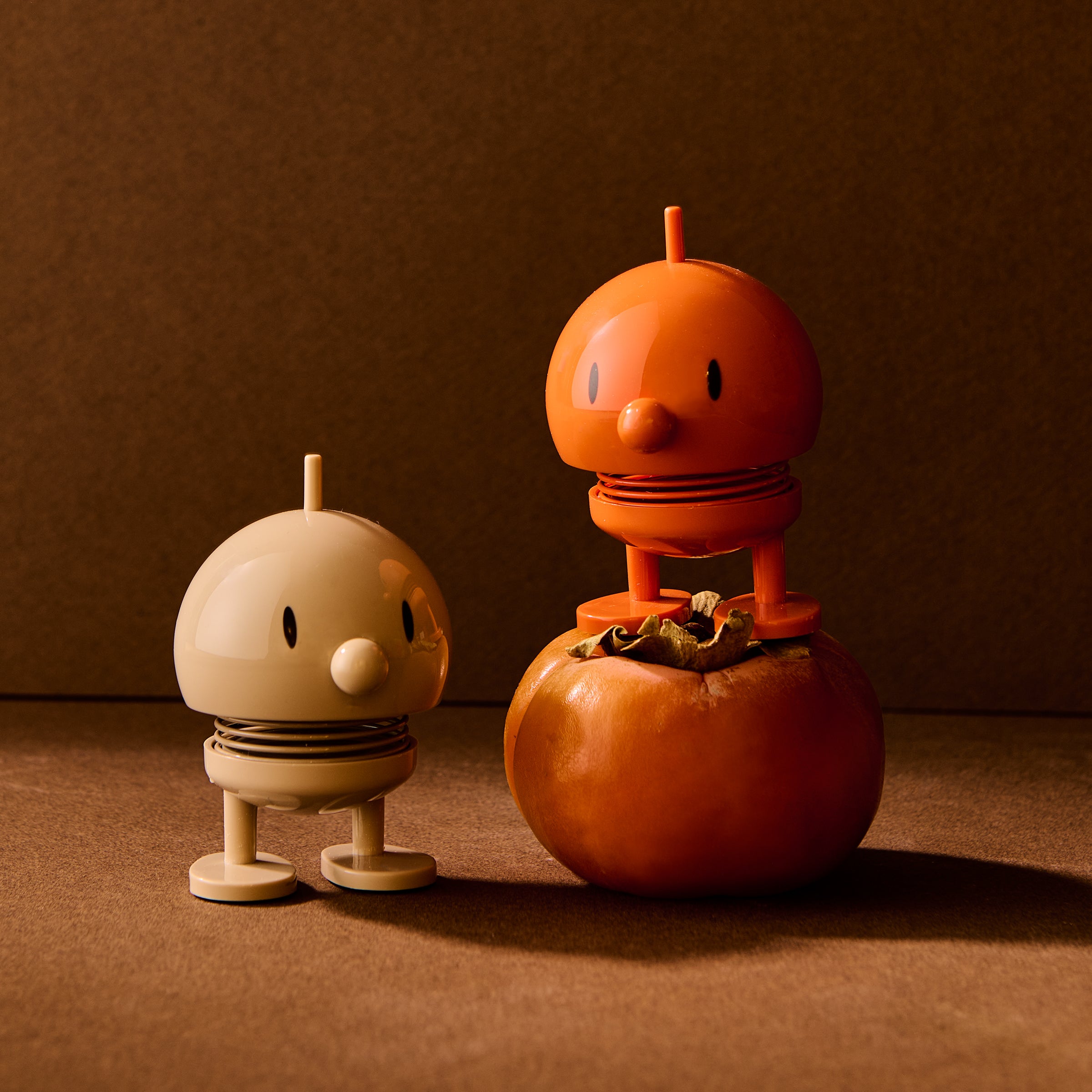 Two small robot-like figures made from pumpkins on a brown background