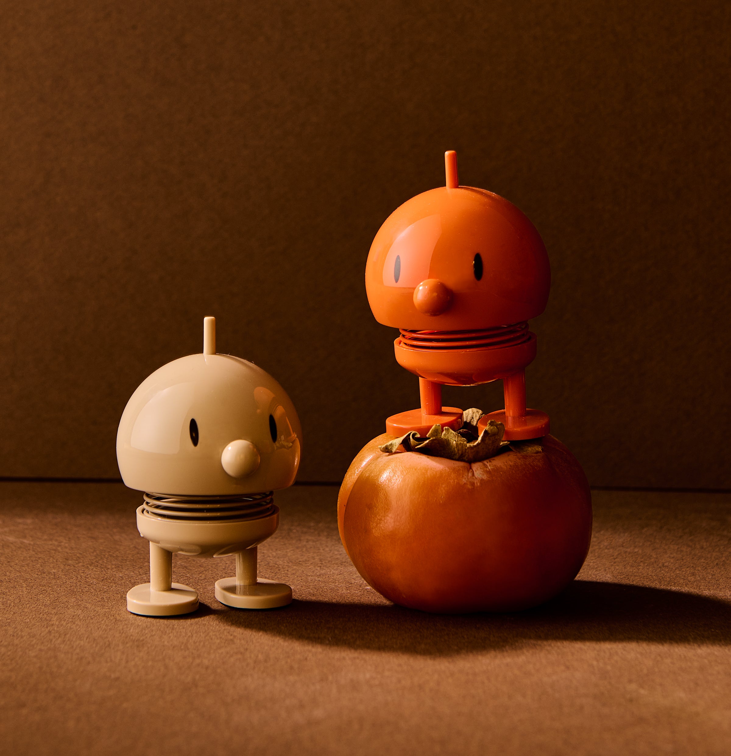 Two small robot-like figures made from pumpkins on a brown background