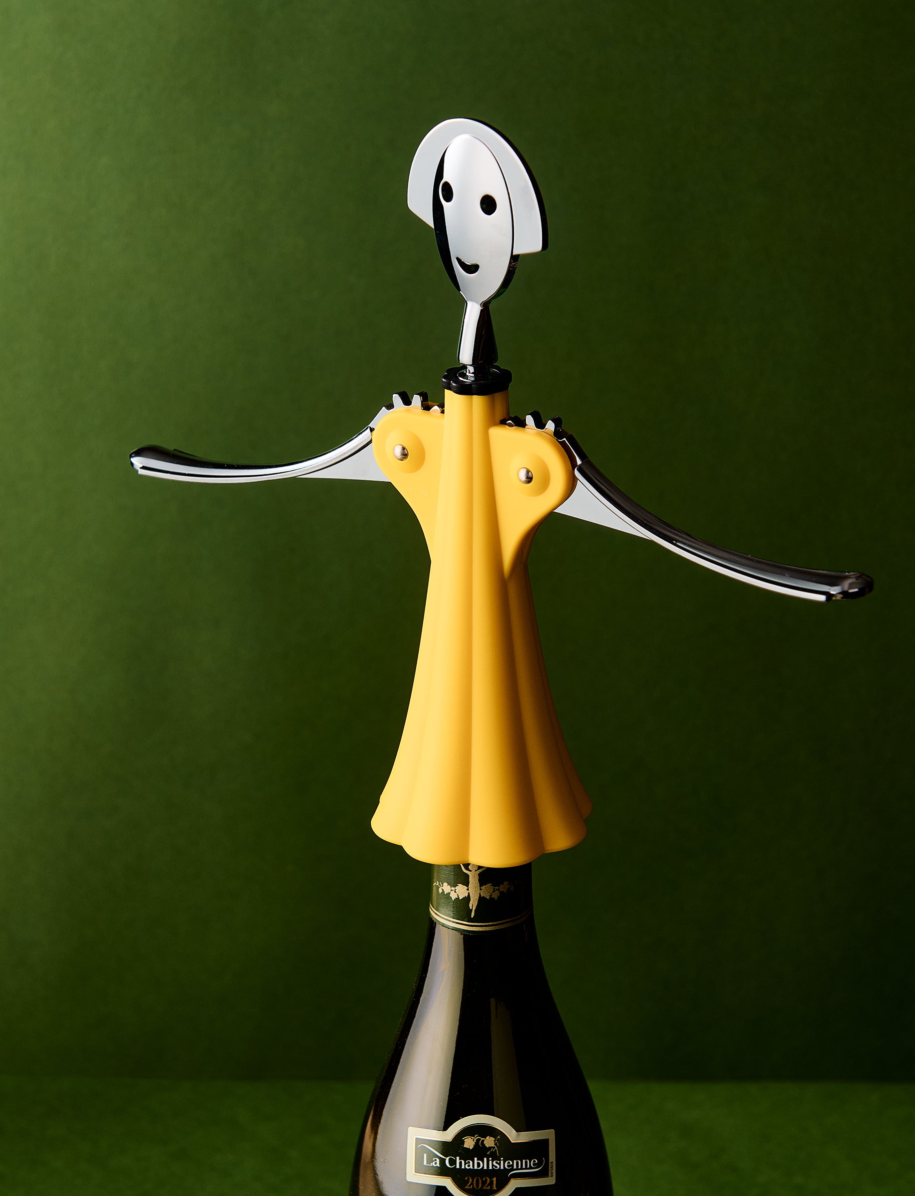 Yellow bottle opener shaped like a person on a wine bottle against a green background