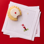 Stack of white napkins with embroidered design on a red background
