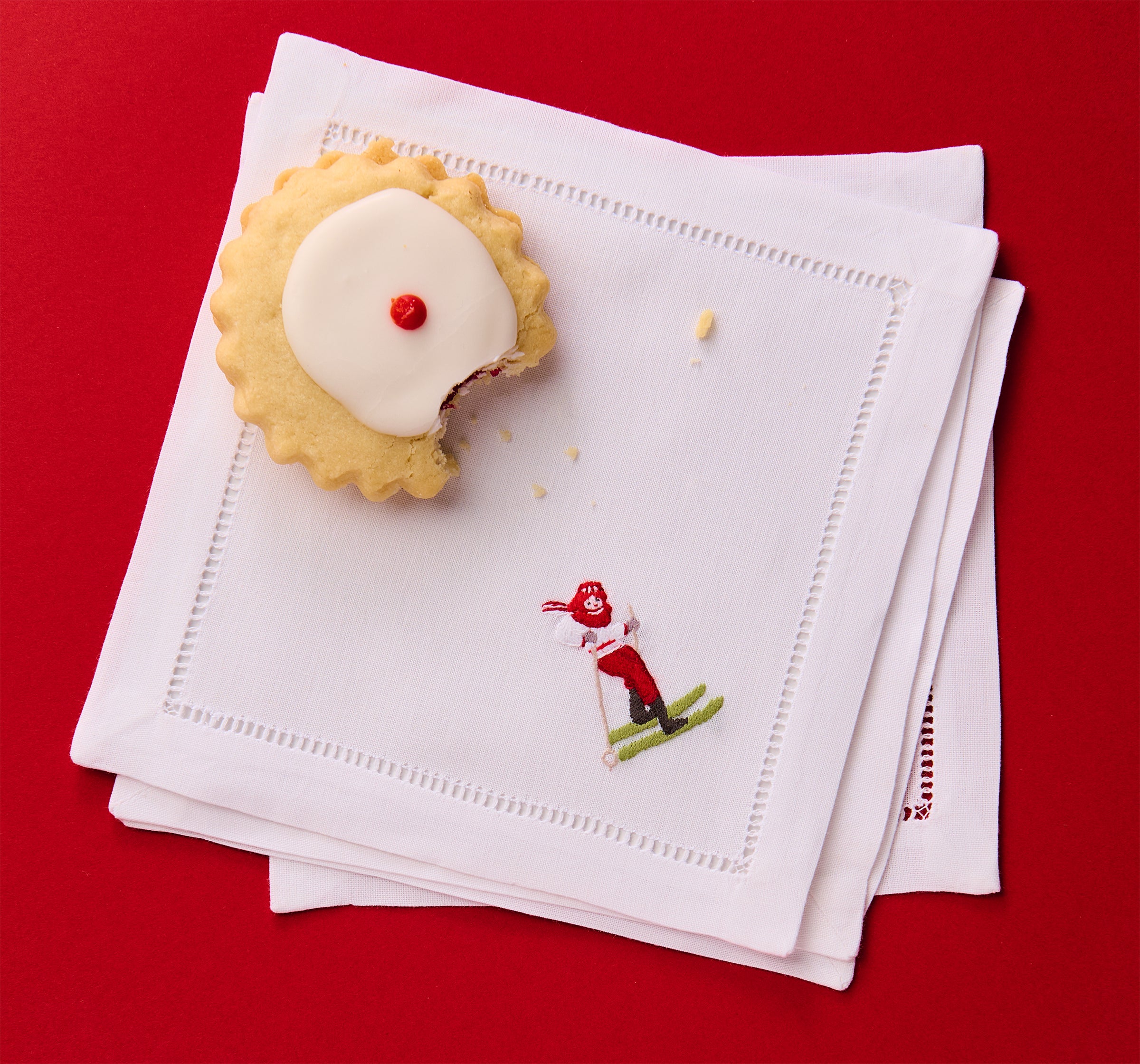 Stack of white napkins with embroidered design on a red background