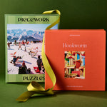 Two puzzle boxes, one green and one orange, with a yellow ribbon on a green background.