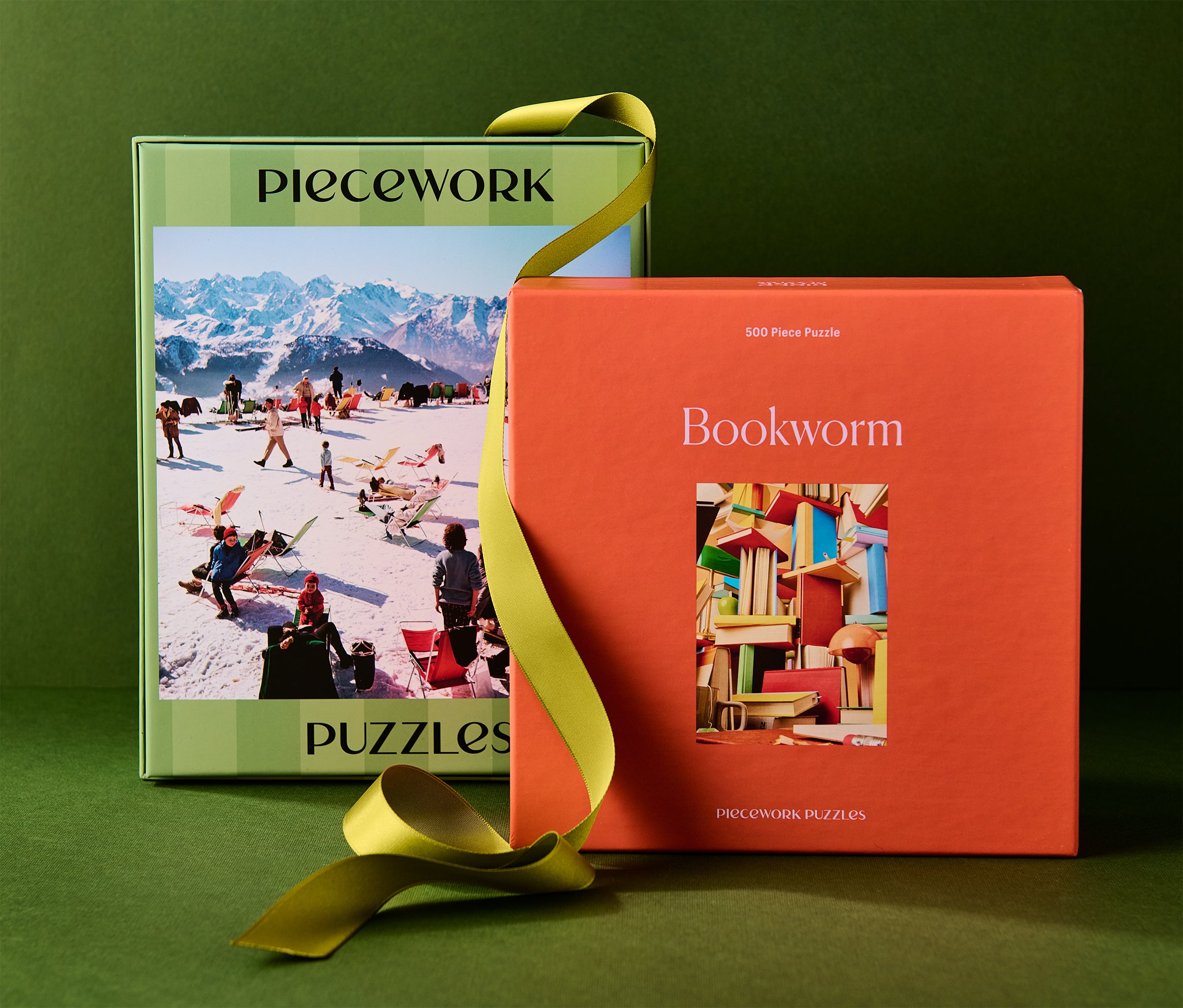Two puzzle boxes, one green and one orange, with a yellow ribbon on a green background.