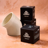 Black boxes with 'Sel Saint Laurent' branding on a textured surface.