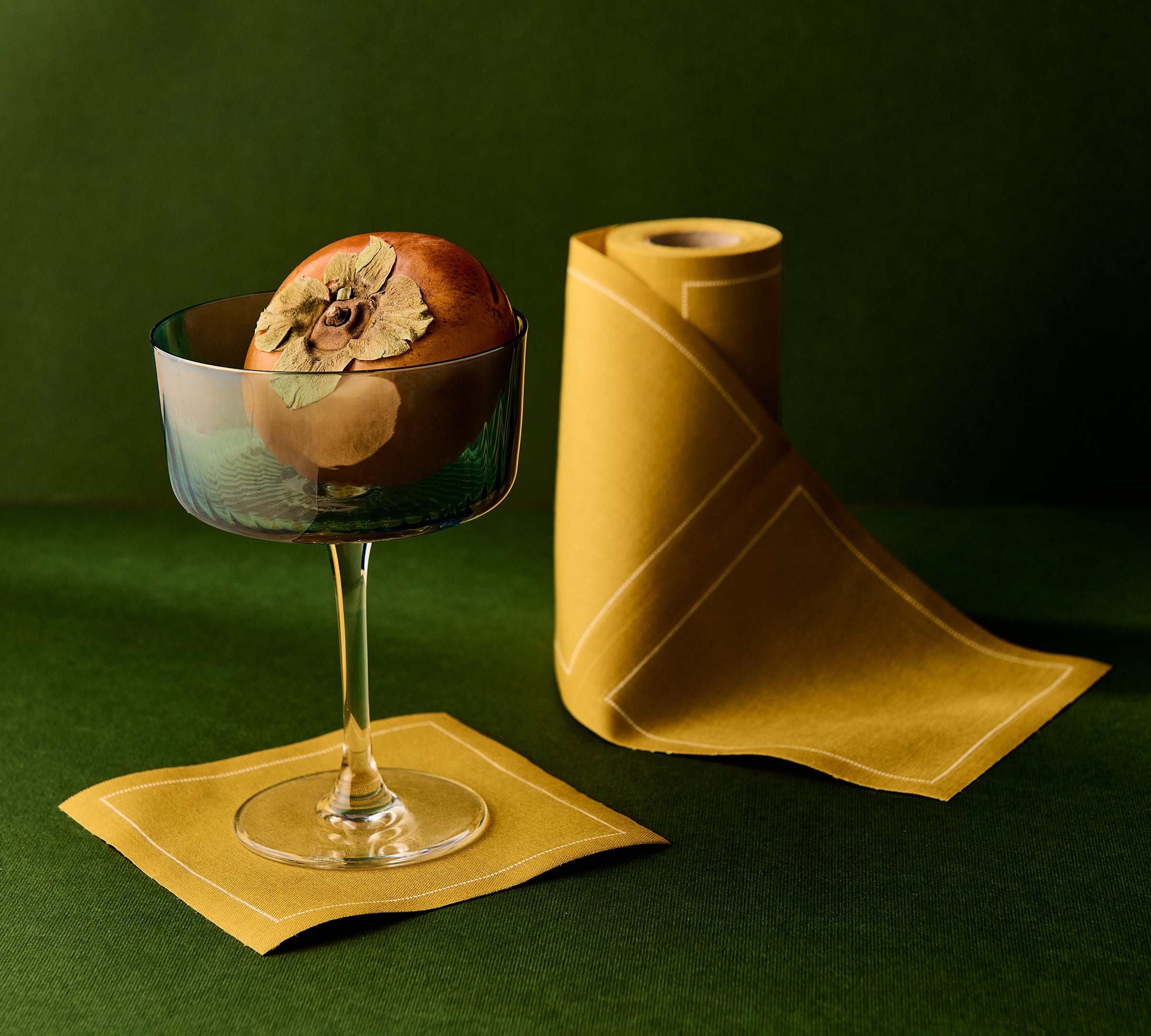 Cocktail glass with a decorative element on a green background and yellow napkin