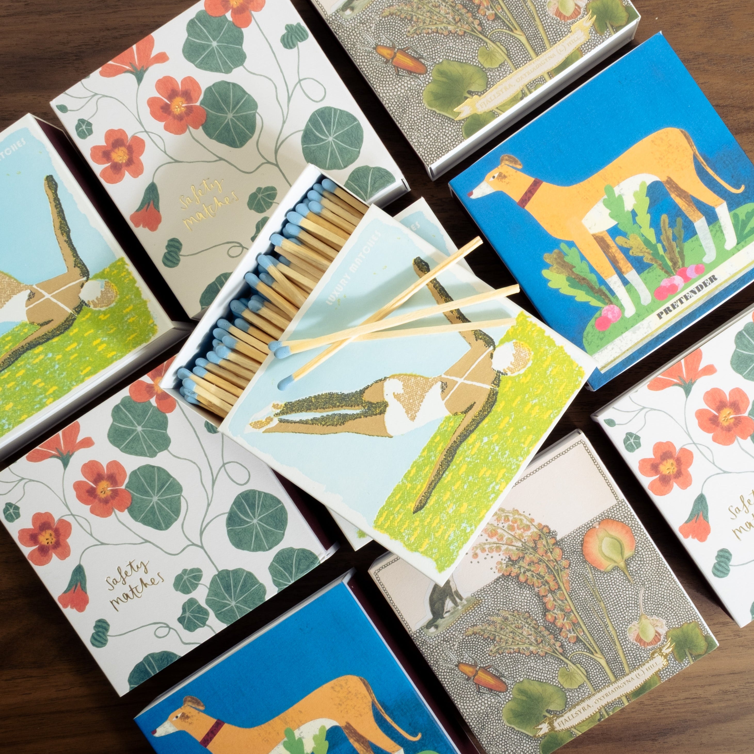 Collection of matchboxes with animal and floral designs on a wooden surface