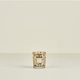 Decorative candle holder with gold and black pattern on a beige background