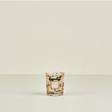 Decorative glass candle holder with intricate design on a beige background