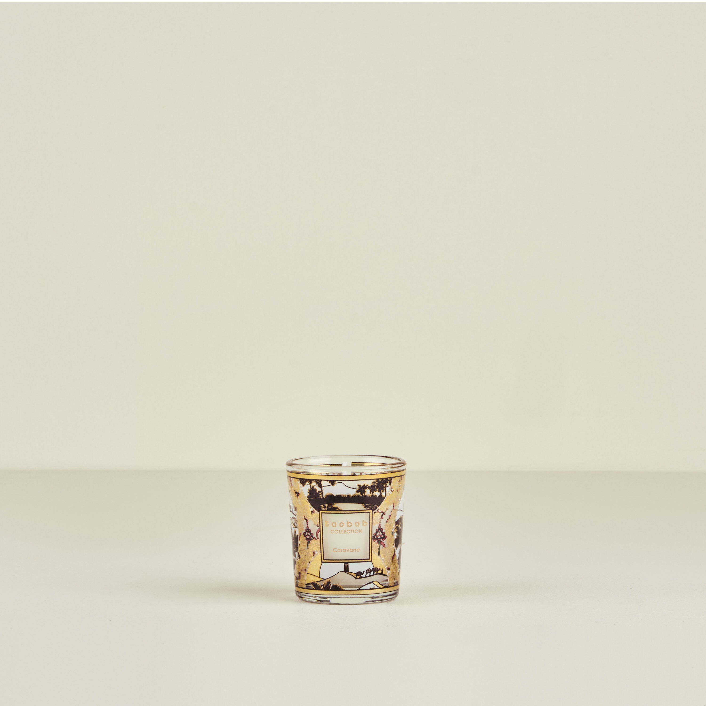 Decorative glass candle holder with intricate design on a beige background