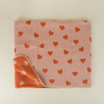 Folded blanket with heart patterns on a light background