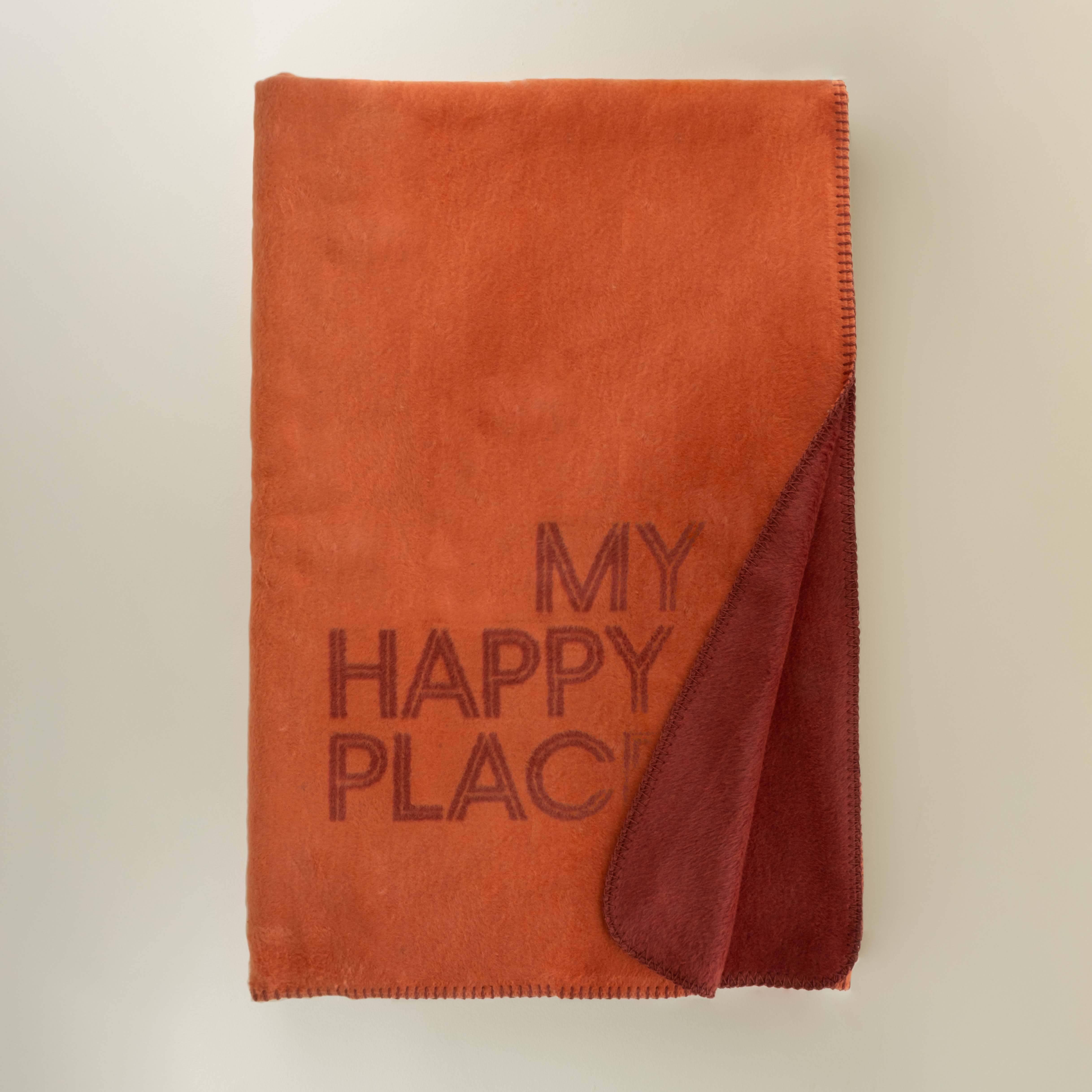 Brown blanket with 'My Happy Place' text on a beige background