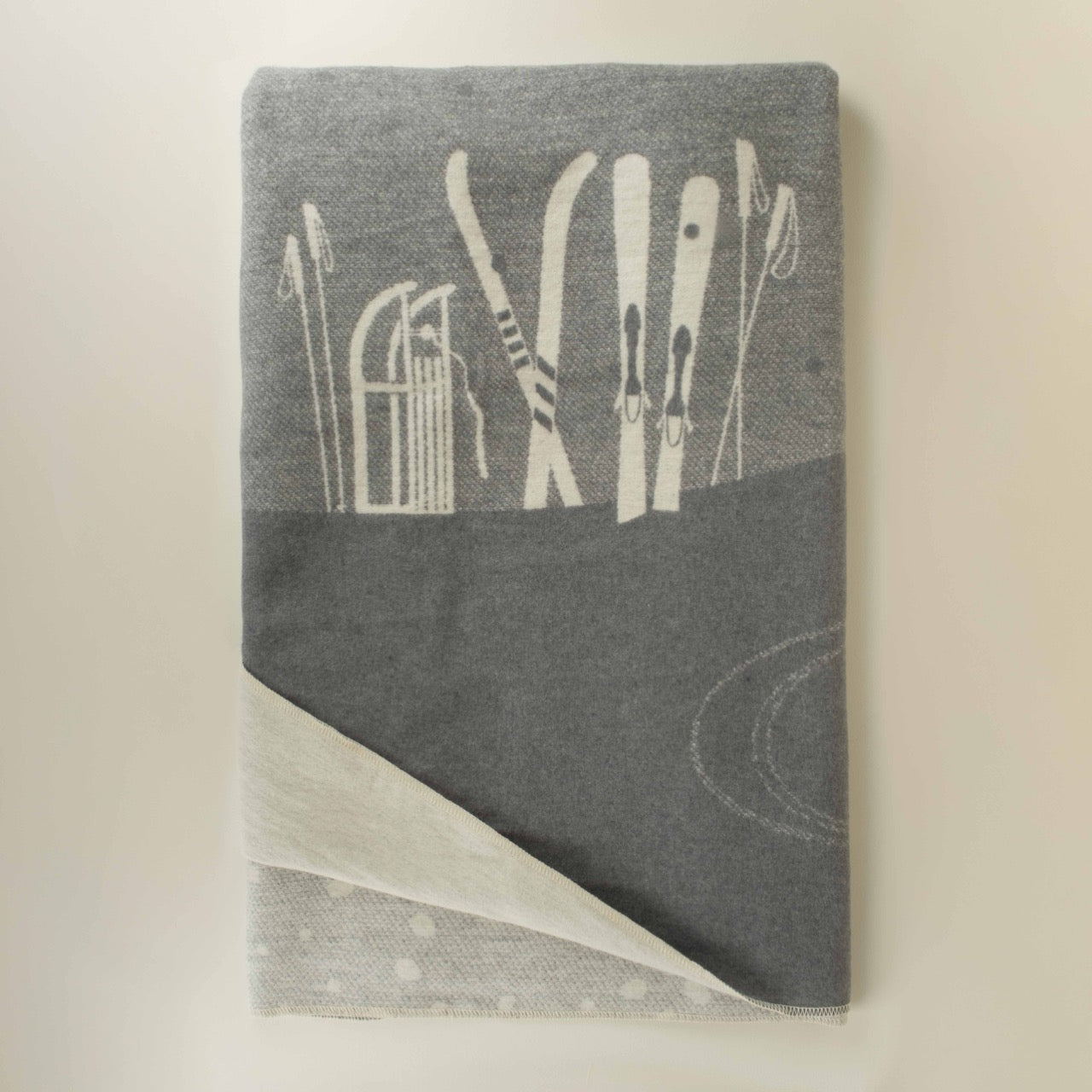 Gray blanket with white ski patterns on a beige background