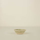 Small ceramic bowl with a green rim on a beige background