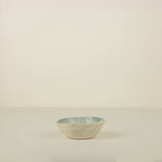 Small ceramic bowl with blue rim on a beige background