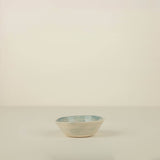 Small ceramic bowl with blue rim on a beige background