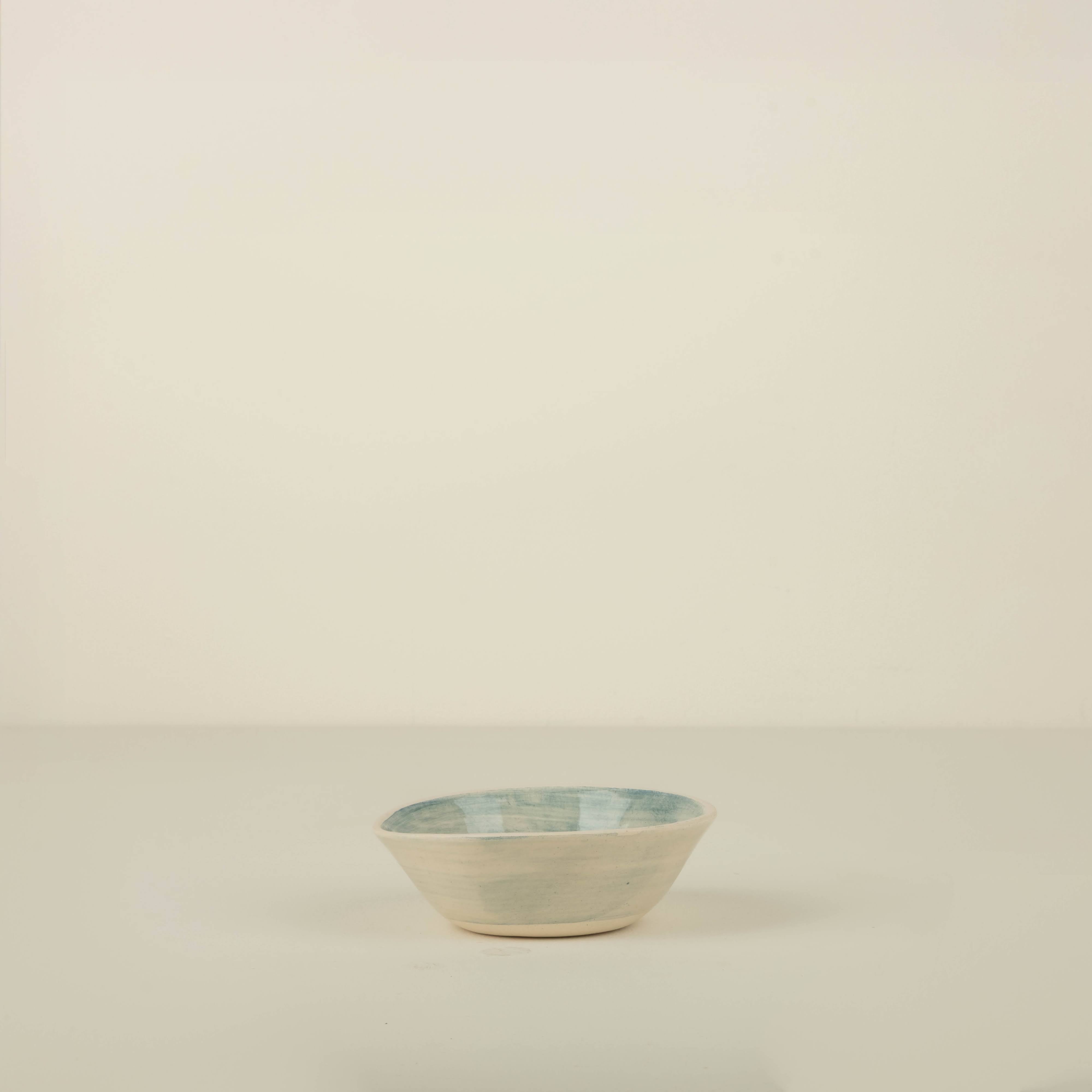 Small ceramic bowl with blue rim on a beige background