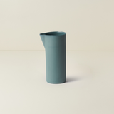 Blue ceramic pitcher on a beige background