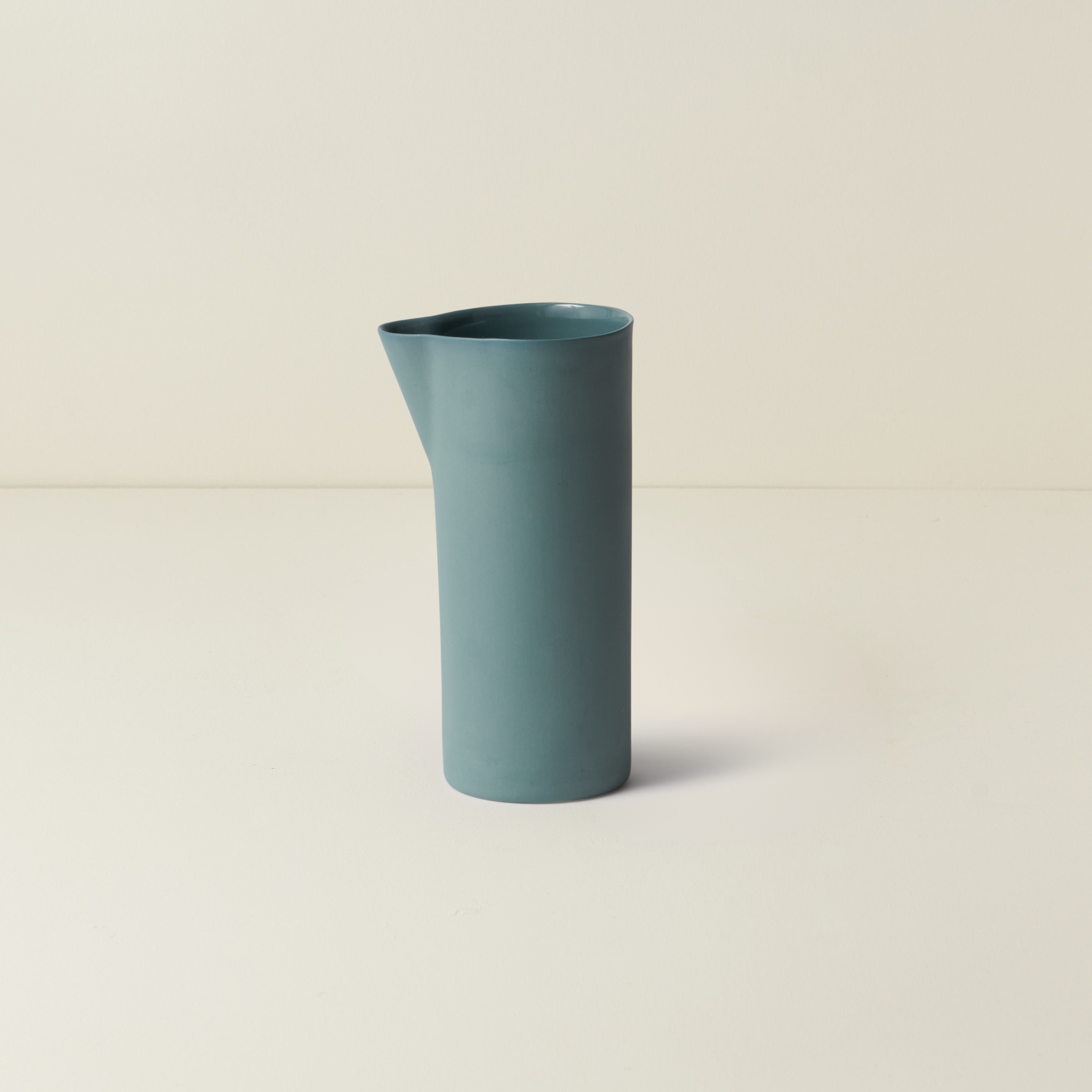 Blue ceramic pitcher on a beige background