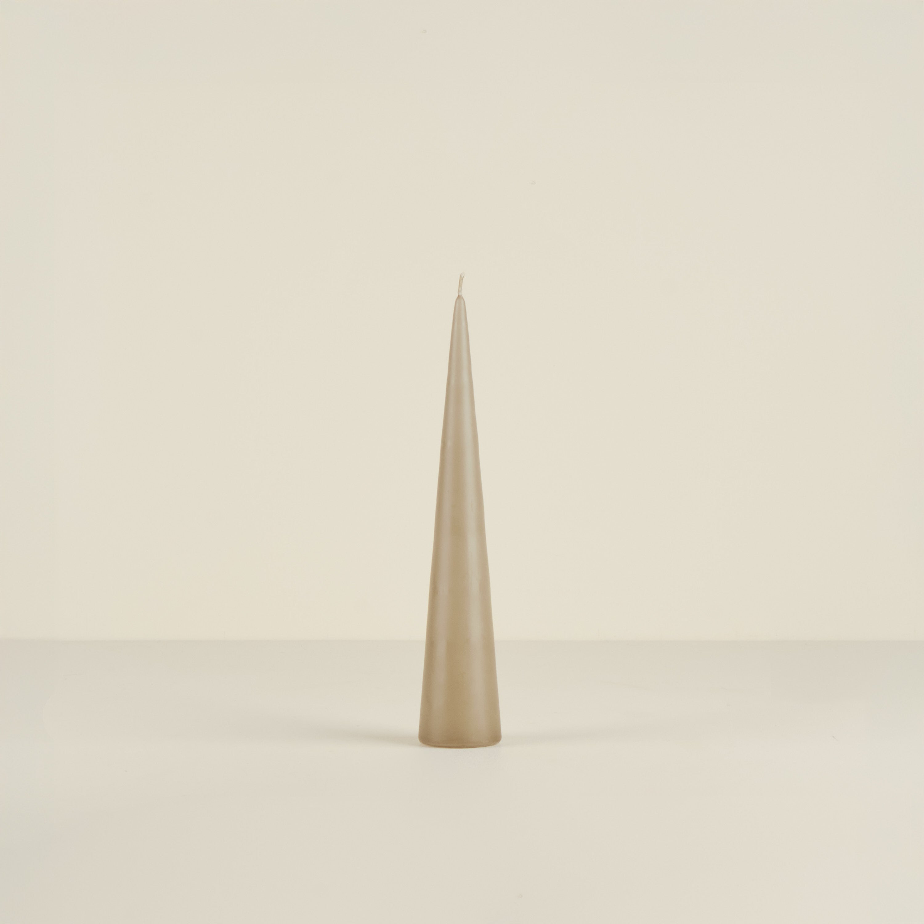 Tapered beige candle on a beige background