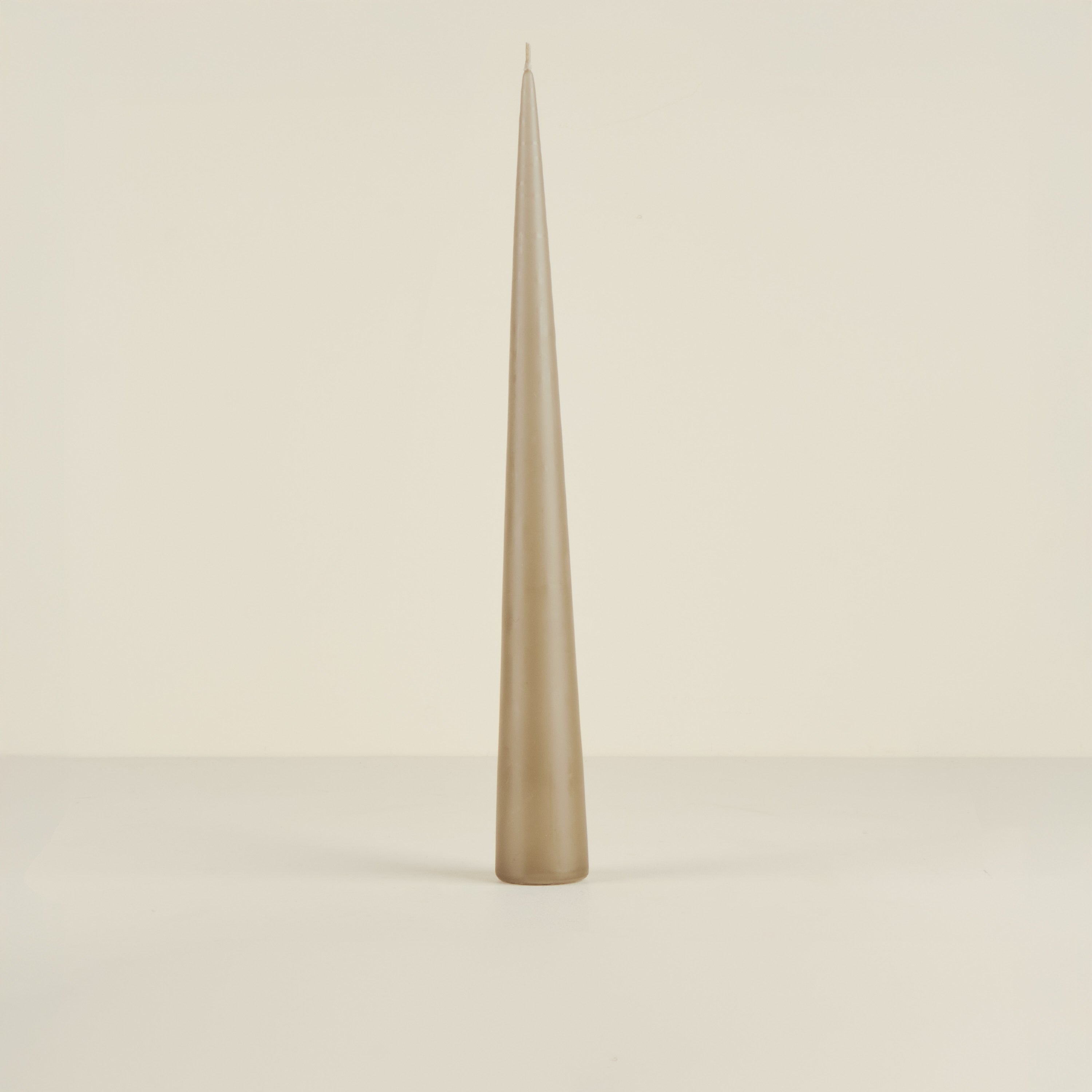 Tapered beige candle on a light beige background