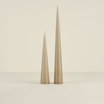 Two beige taper candles on a beige background