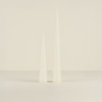 Two white candles on a light beige background