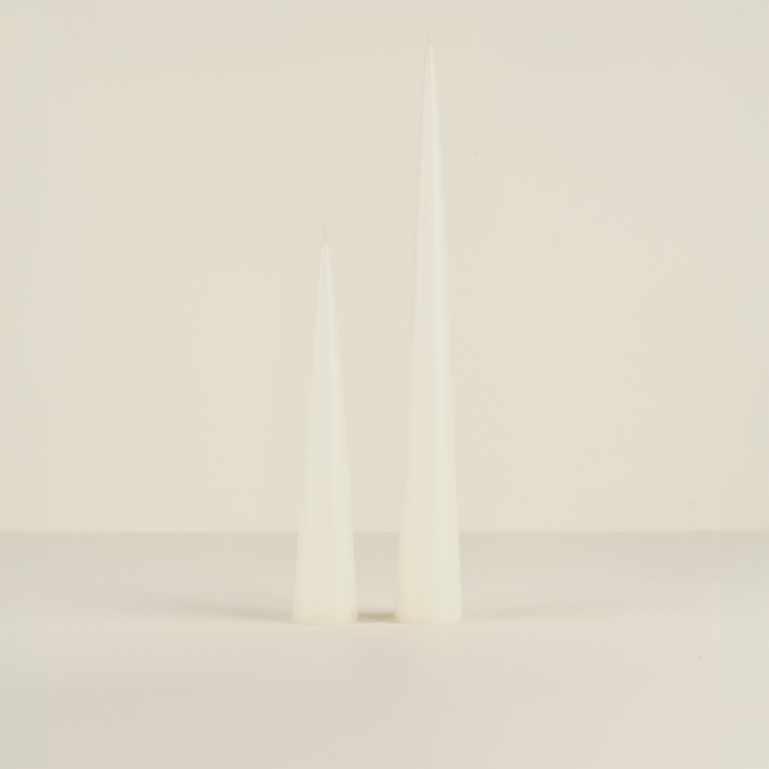 Two white candles on a light beige background