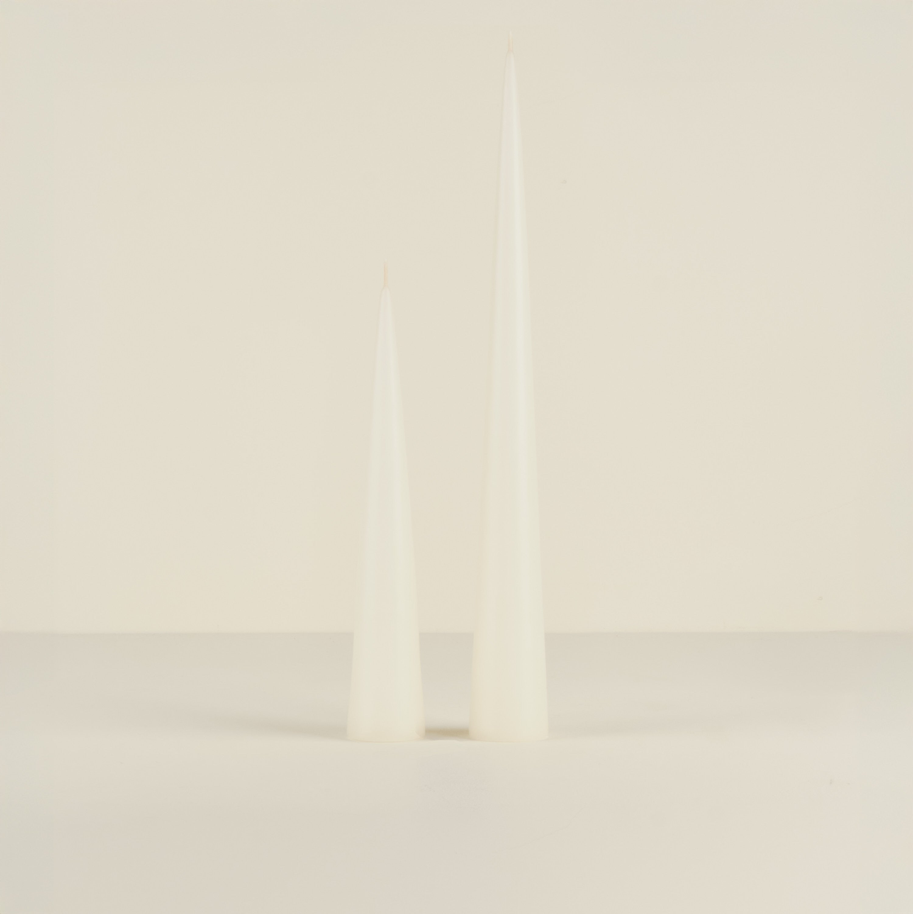 Two white candles on a light beige background