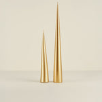 Two gold taper candles on a beige background
