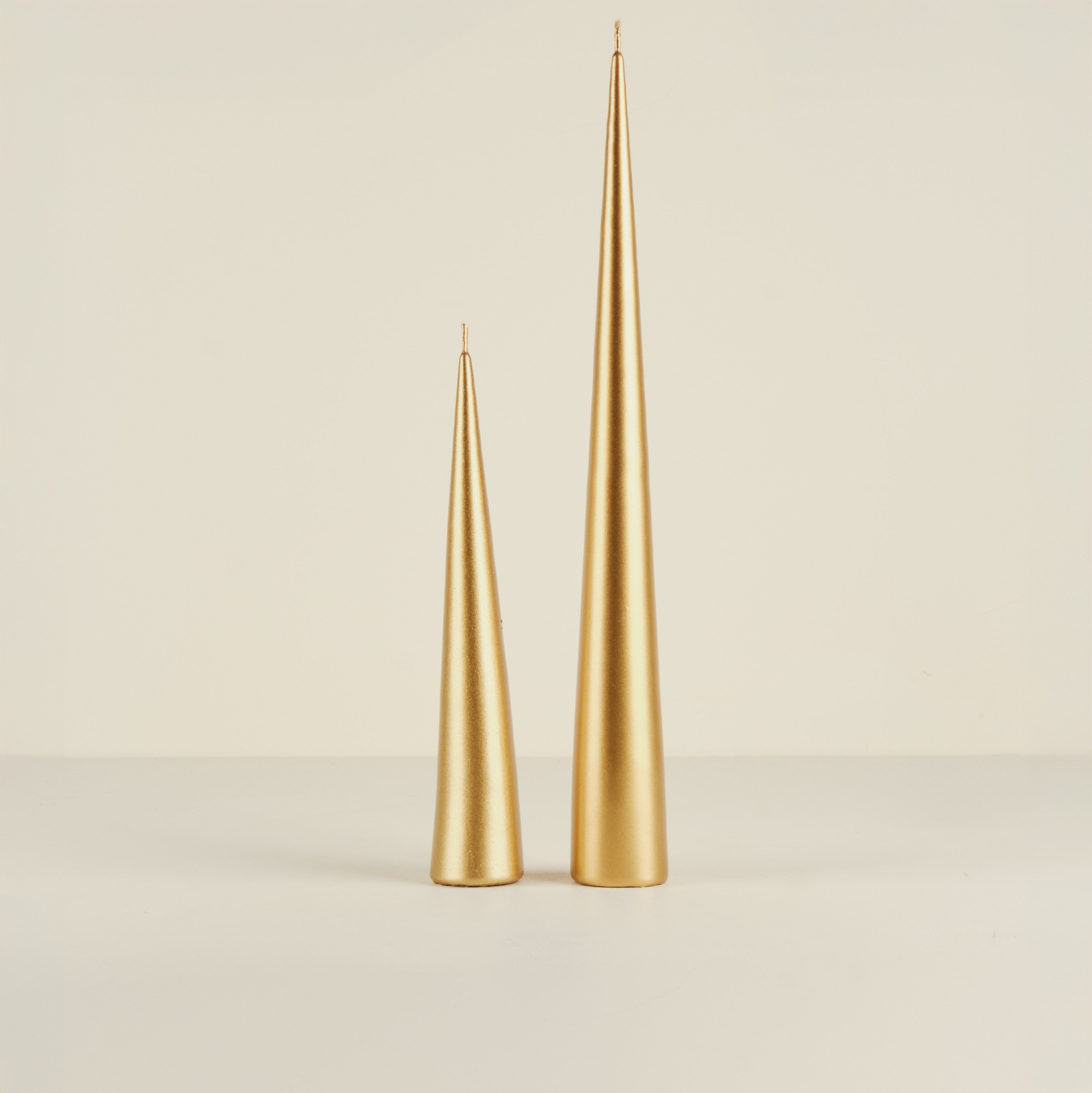 Two gold taper candles on a beige background