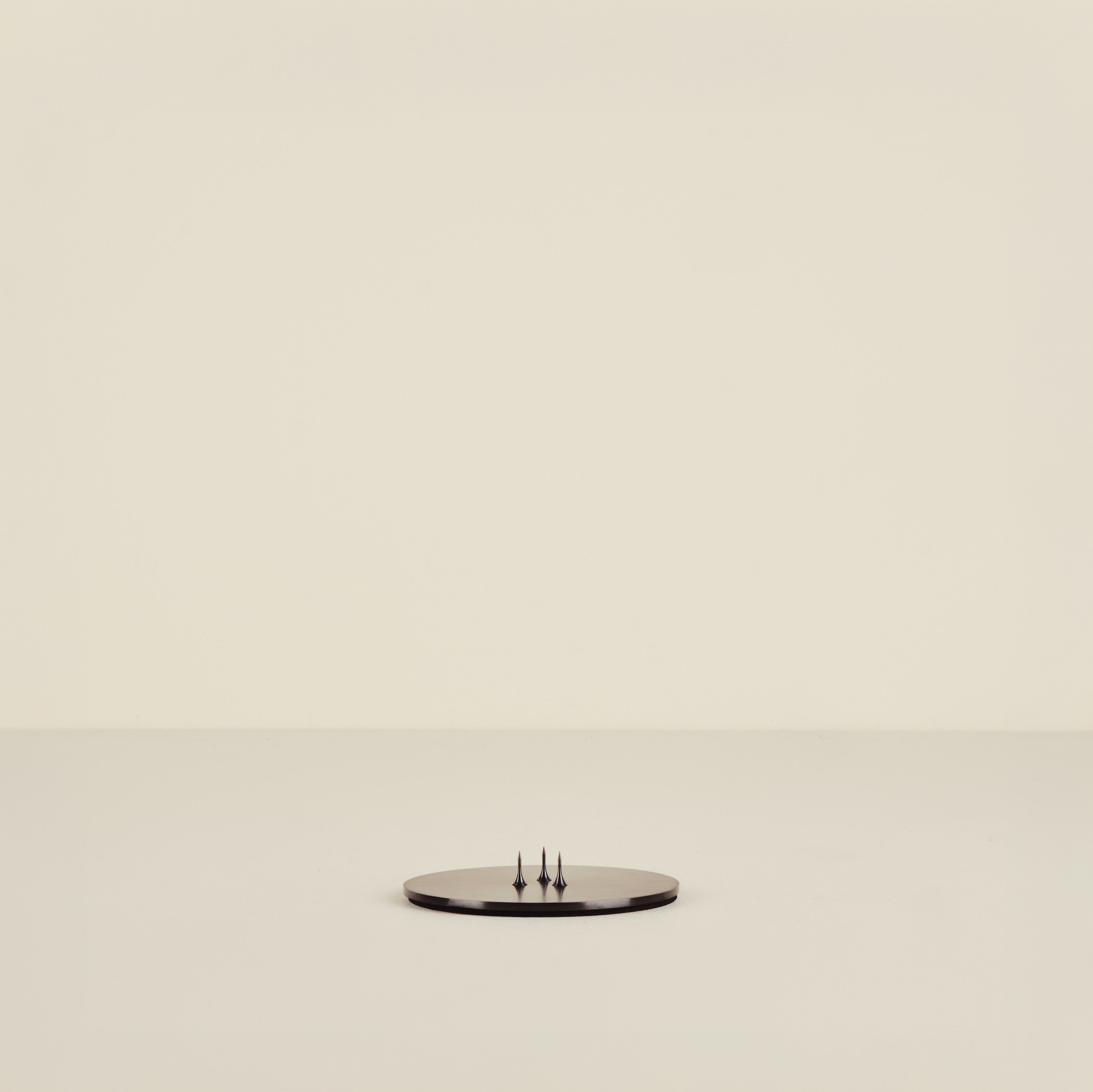 Small round candle plate with three legs on a beige background