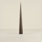 Tapered black candle on a beige background