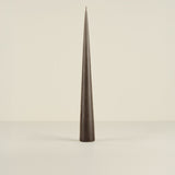Tapered black candle on a beige background