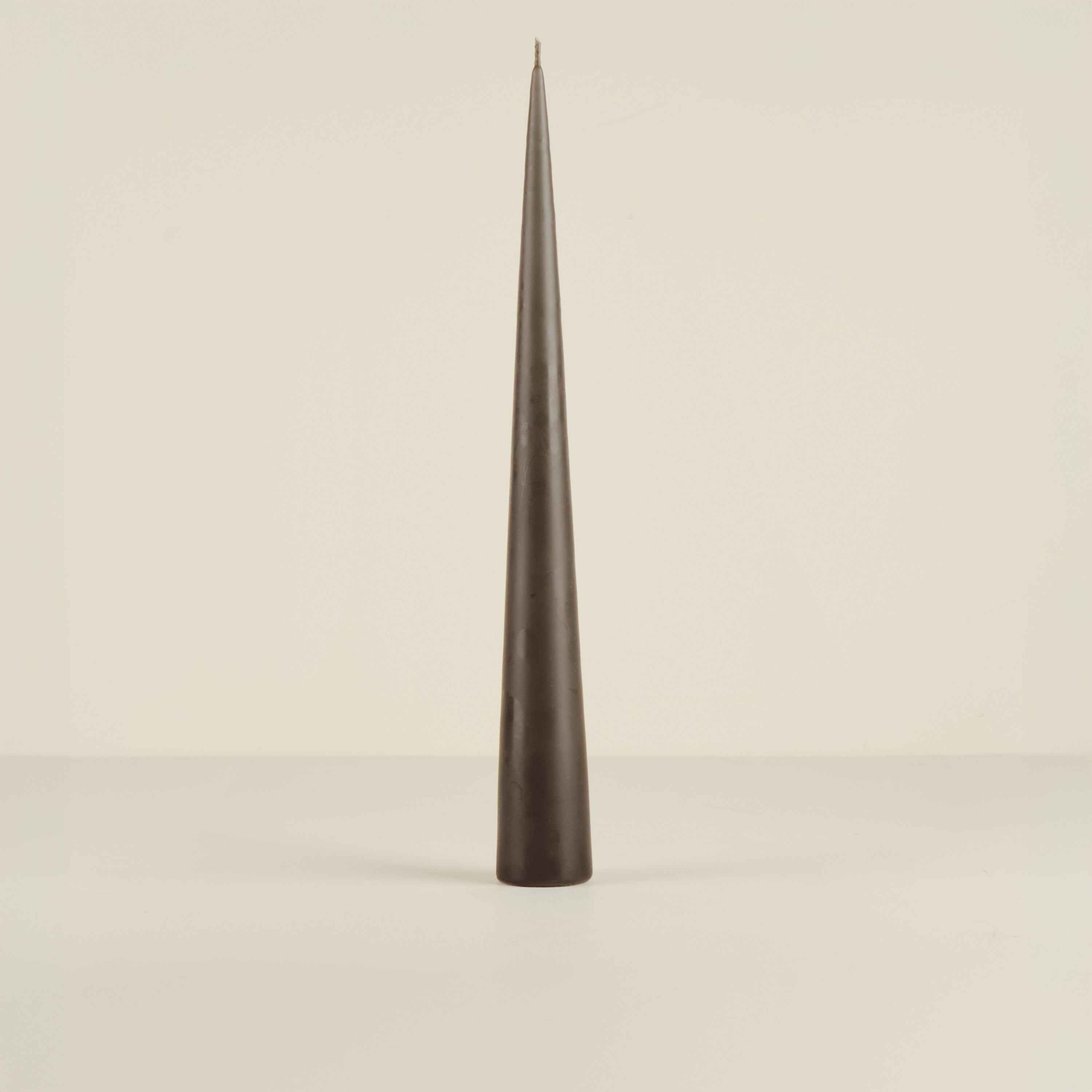 Tapered black candle on a beige background