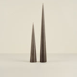 Two tall, dark gray candles on a beige background