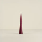 Conical burgundy candle on a beige background