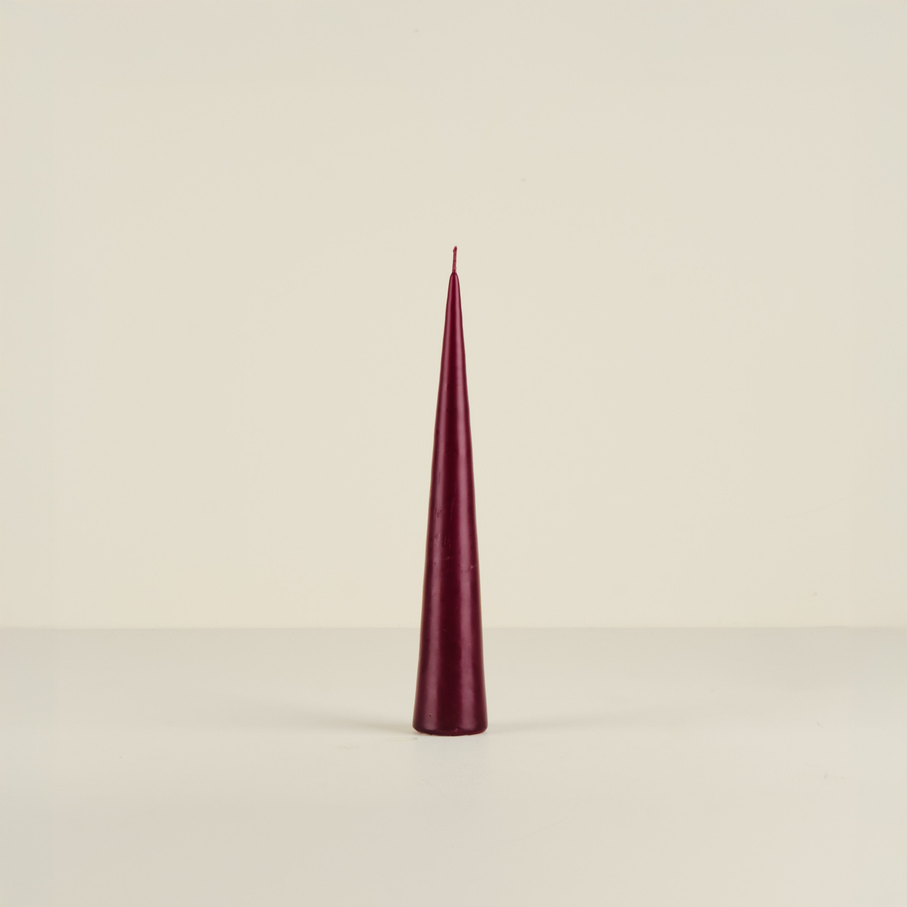 Conical burgundy candle on a beige background