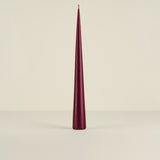 Maroon cone-shaped candle on a beige background