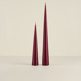Two burgundy taper candles on a beige background